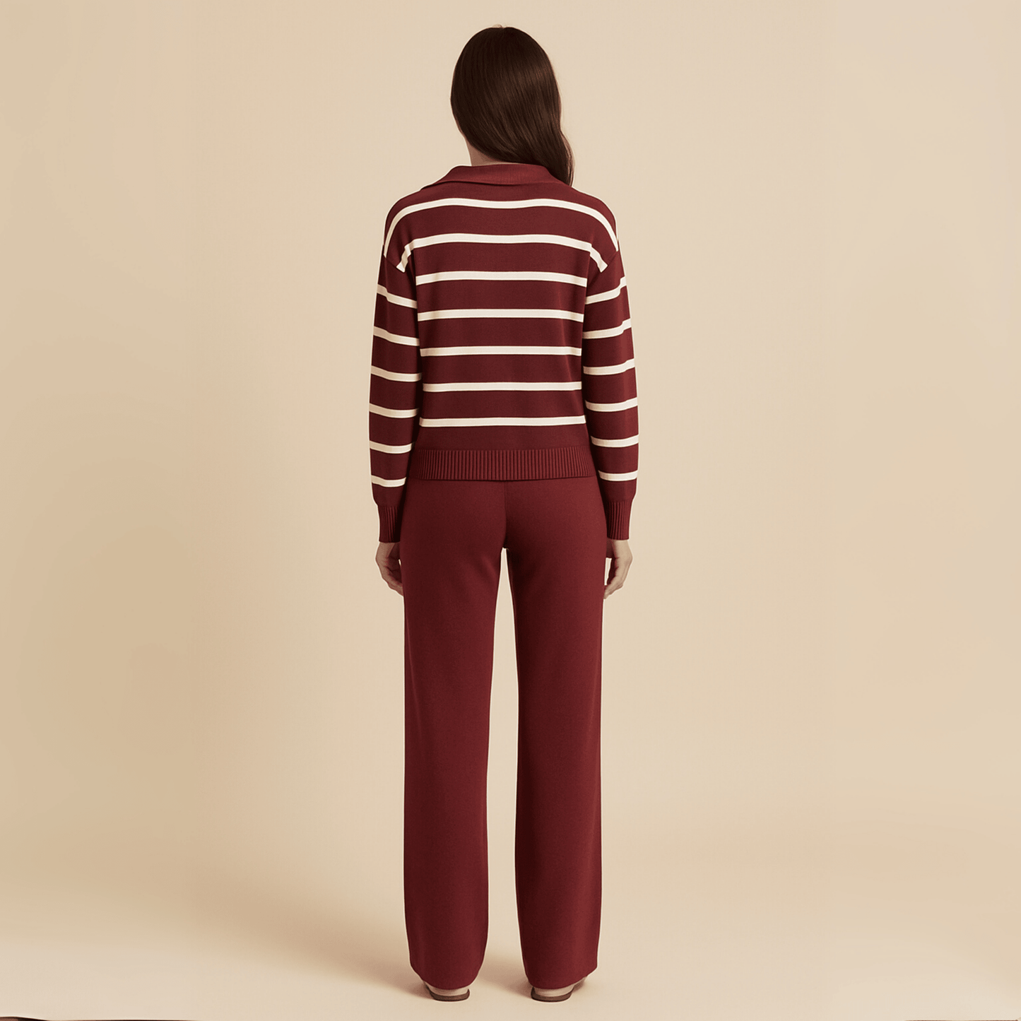 Person wearing a maroon and white striped sweater with matching pants on a beige background
