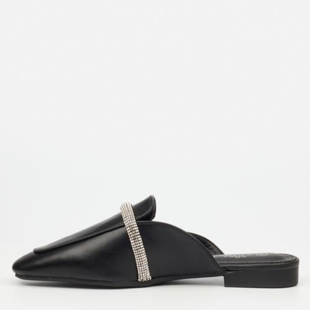 A sleek black mule featuring a minimalist design, elevated by a shimmering rhinestone accentby by Miss Black