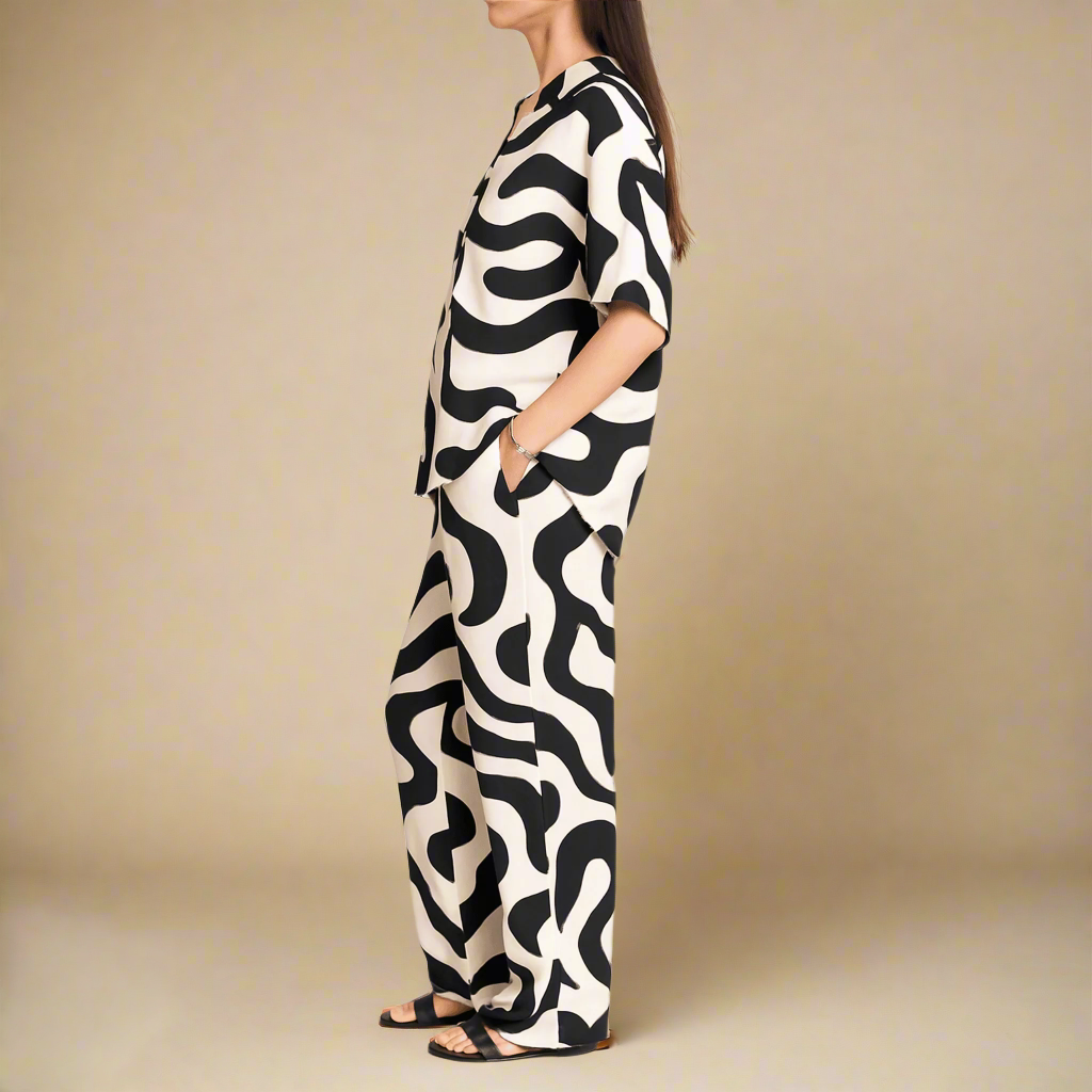 Stylish co-ord from Modern Dynasty’s Moolit Majesty line, showcasing an oversized shirt and matching wide-leg pants printed with black wave-like patterns on white fabric.